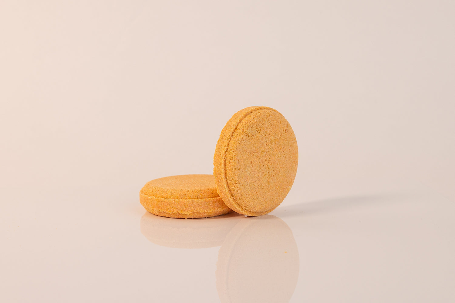 Two CELESTE NATURALS CITRUS shower steamer tablets on a beige background