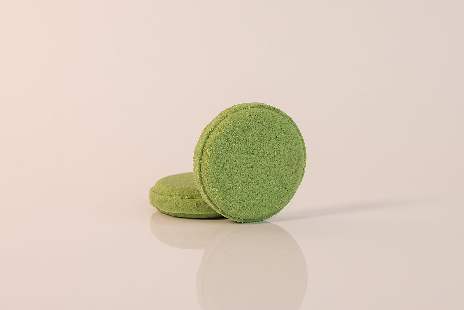 Two CELESTE NATURALS EUCALYPTUS + MINT shower steamers on a reflective surface with a beige background