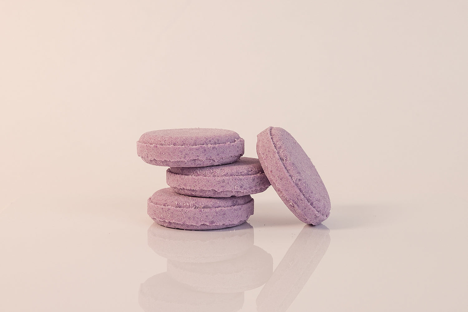 Stack of CELESTE NATURALS LAVENDER shower steamer tablets on a light pink background