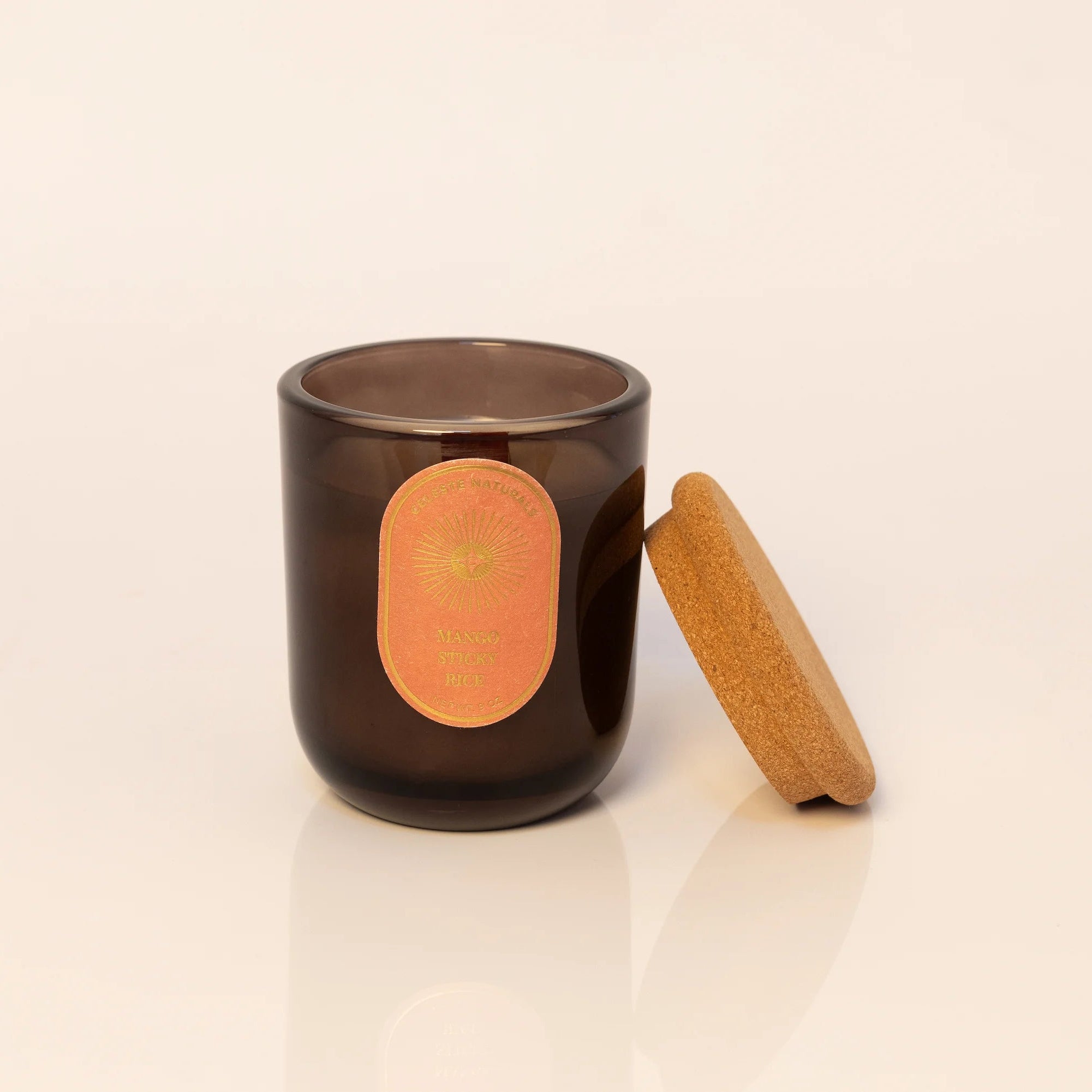 Celeste Naturals Mango Sticky Rice candle in amber vessel with wood wick and cork top