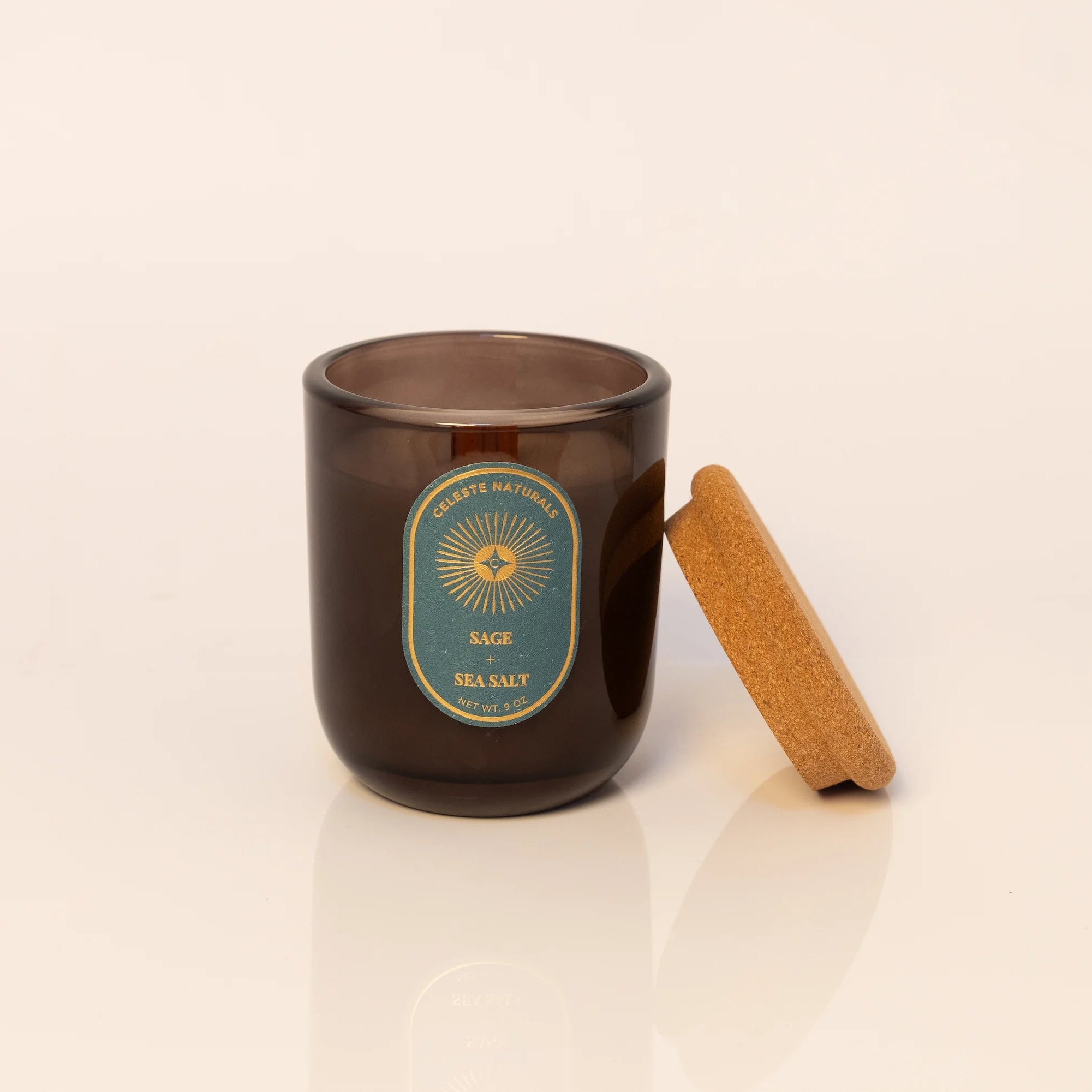 Celeste Naturals Sage + Sea Salt candle in amber vessel with wood wick and cork top.