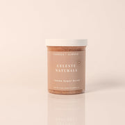 CELESTE NATURALS VANILLA + ALMOND sugar scrub container on a beige background