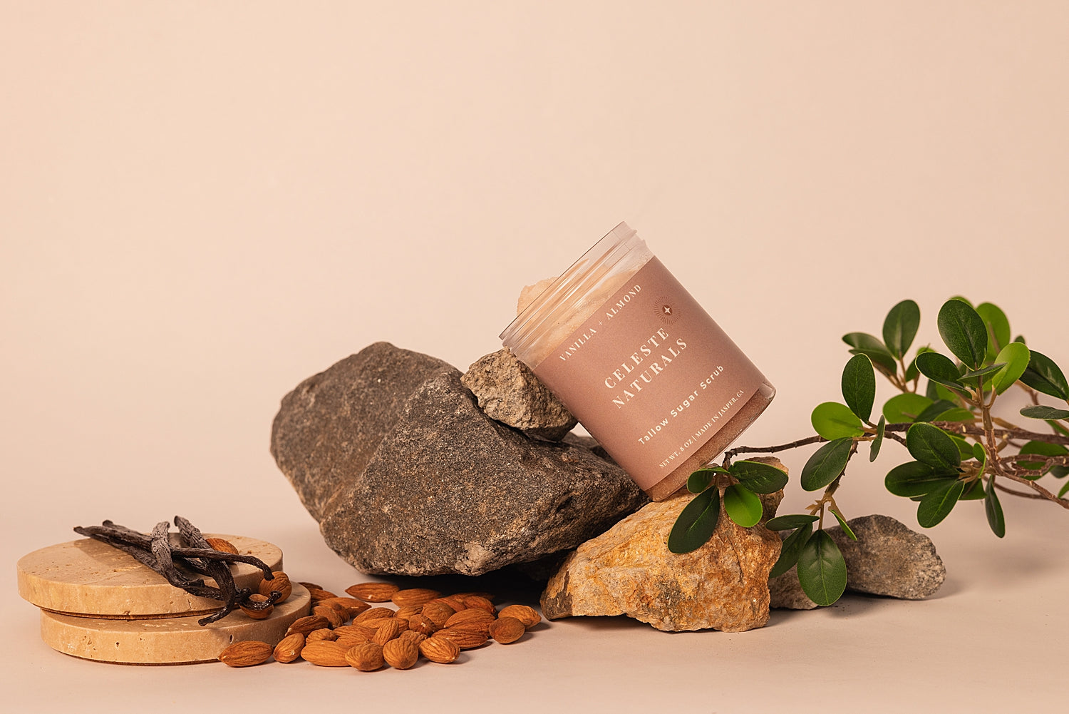 CELESTE NATURALS VANILLA + ALMOND container with natural elements like stones, nuts, and leaves on a beige background
